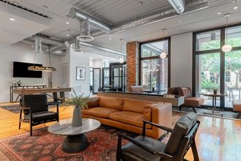 a living room with a couch and chairs and a large window at The Can Plant Residences at Pearl, San Antonio, Texas